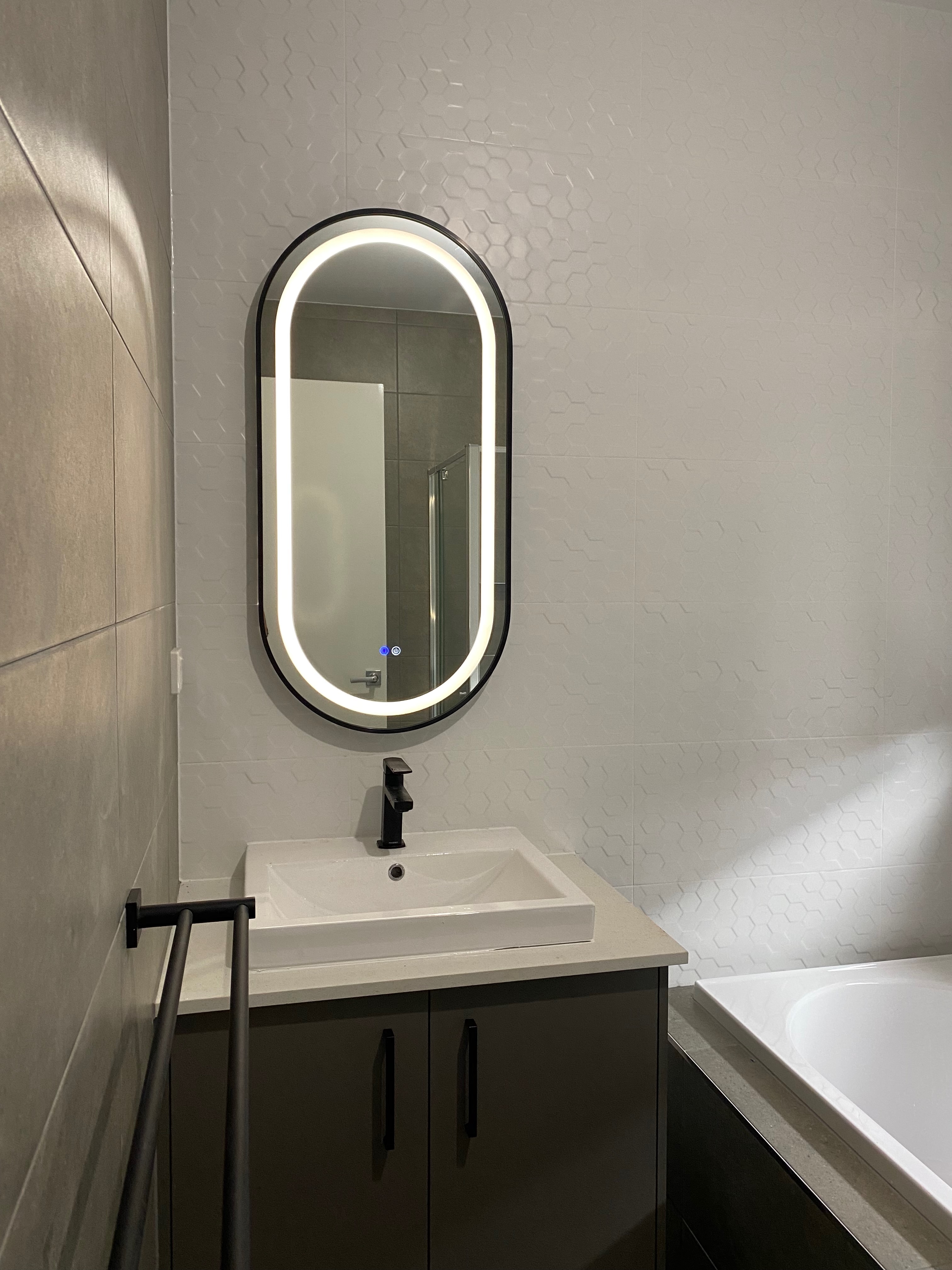Single vanity with oval LED backlit mirror in modern bathroom