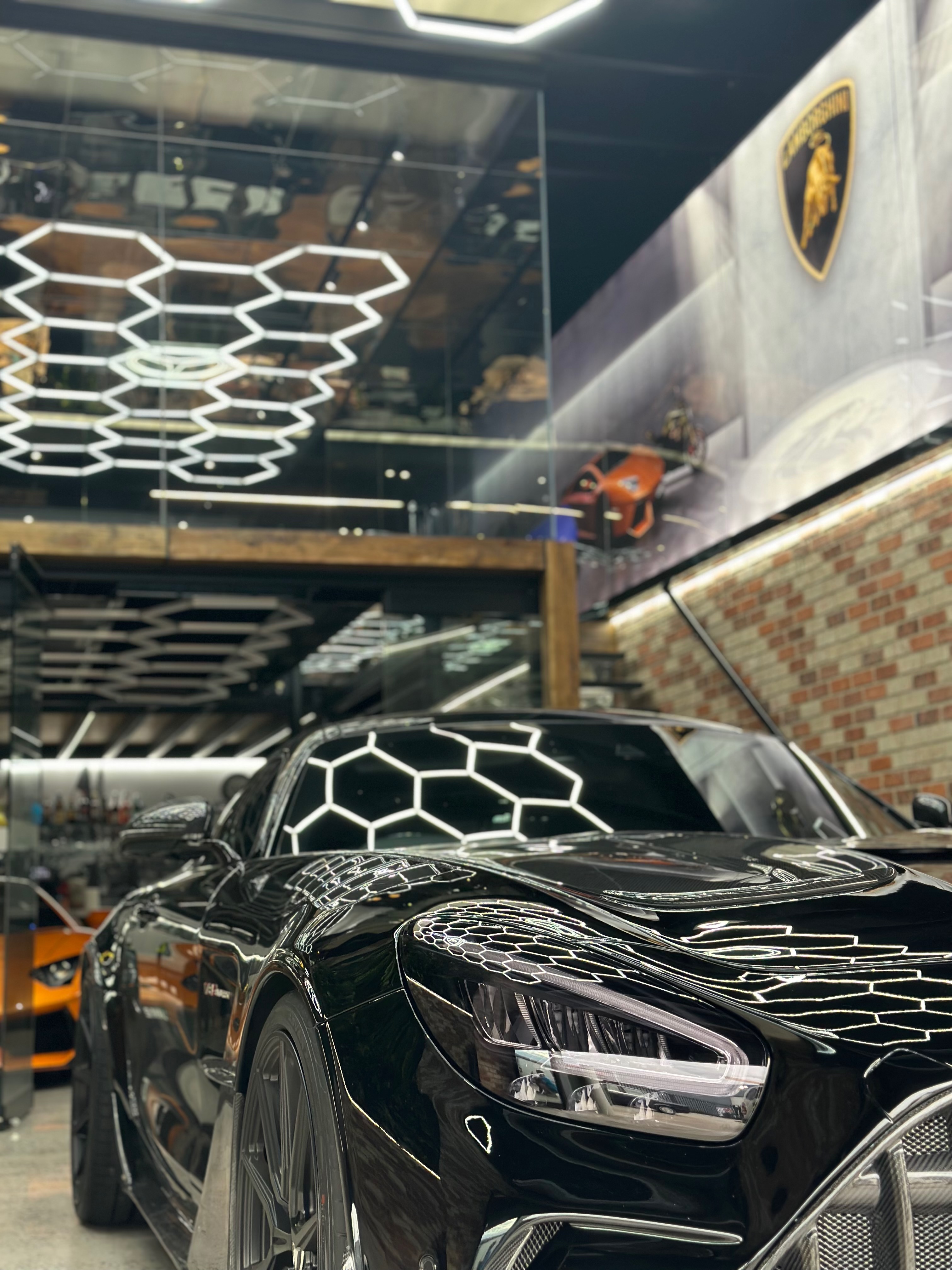 Black Lamborghini sports car with hexagonal ceiling lighting pattern
