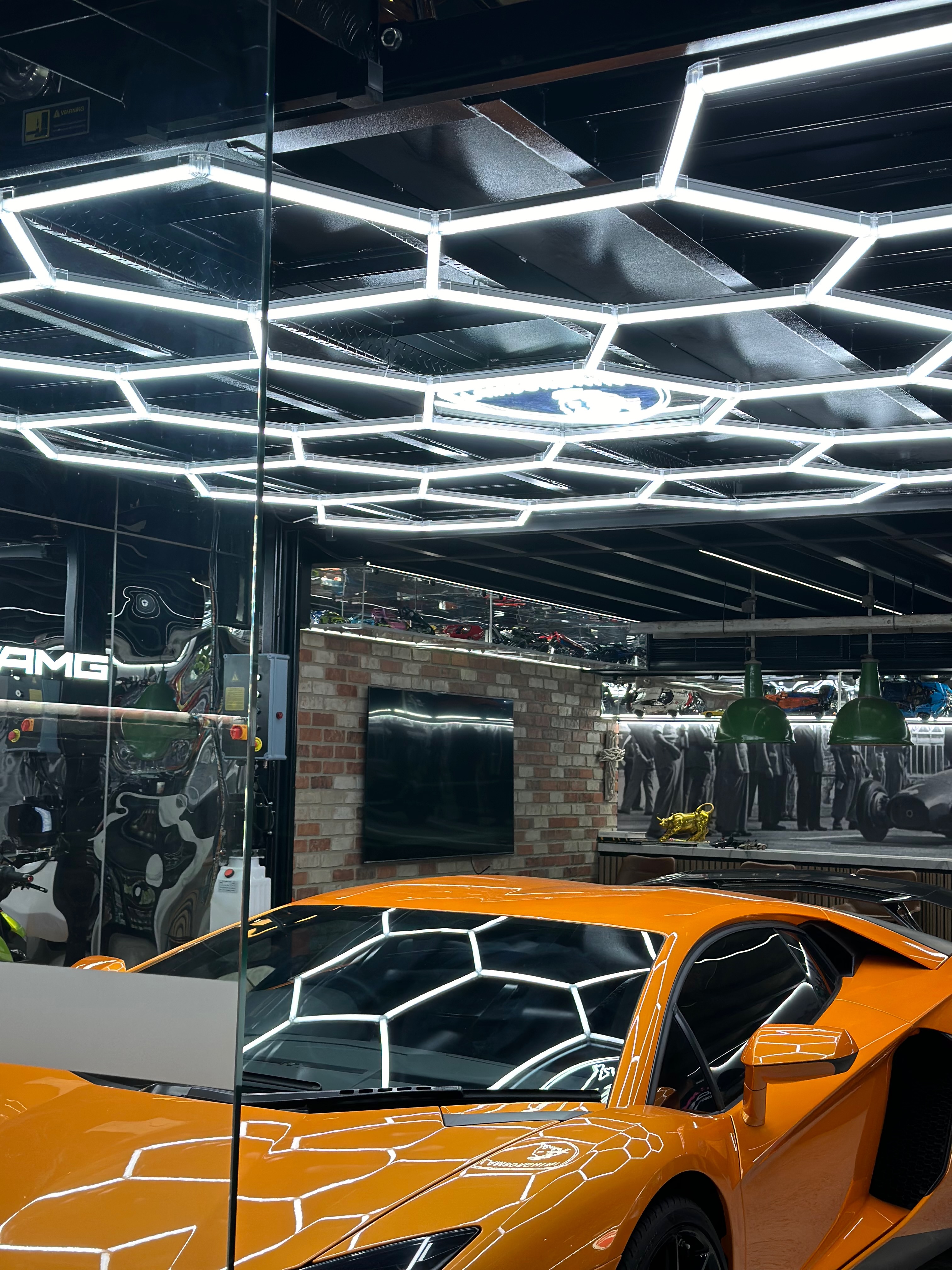 Close-up view of orange Lamborghini under hexagonal ceiling lights